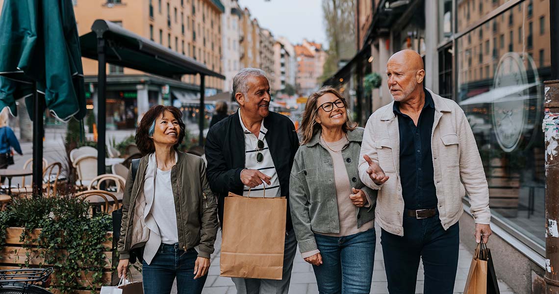 Fyra äldre personer gåendes längs shoppinggata