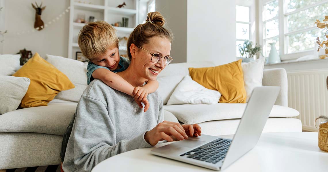Mamma och barn tittar leendes mot laptopskärm