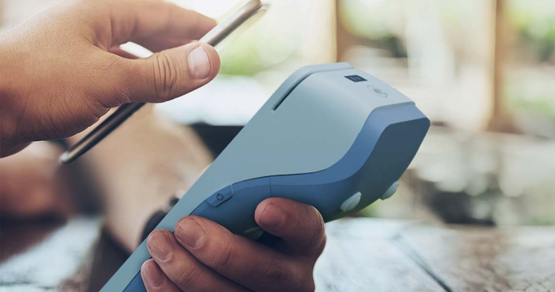 Person betalar med mobil på betalterminal