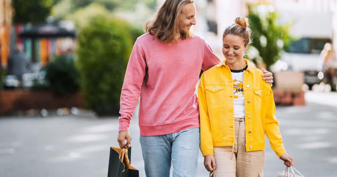 Ett par med shoppingkassar som går och håller om varandra