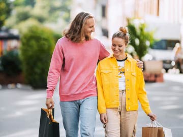 Ett par med shoppingkassar som går och håller om varandra