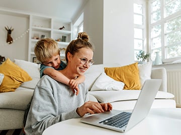 Mamma och barn tittar leendes mot laptopskärm